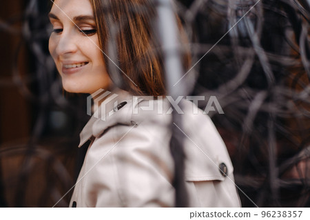 A happy stylish girl In a gray coat is sitting outside in an armchair 96238357
