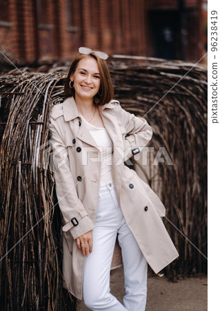 A happy stylish girl in a gray coat walks around the city A happy stylish girl in a gray coat walks around the city 96238419