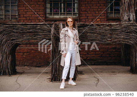 A happy stylish girl in a gray coat walks around the city A happy stylish girl in a gray coat walks around the city 96238540