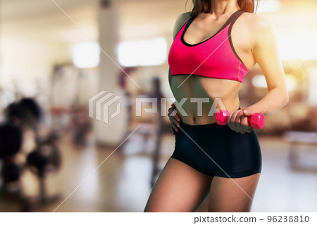 Muscular woman is training with weight dumbbells at the gym 96238810