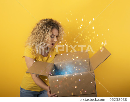 Happy girl receives a package from online shop order. Yellow background. Happy girl receives a package from online shop order. Yellow background. 96238988