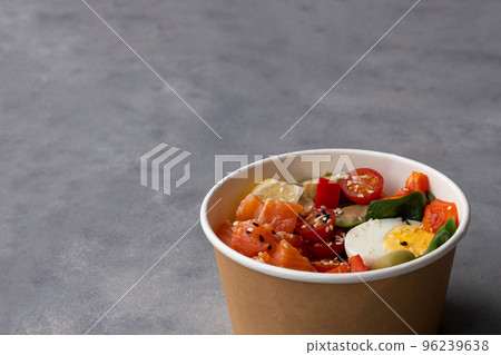 Takeaway poke bowl with fresh salmon, avocado, quinoa and vegetables in recycled kraft paper packaging. Healthy Trendy Fitness food. 96239638