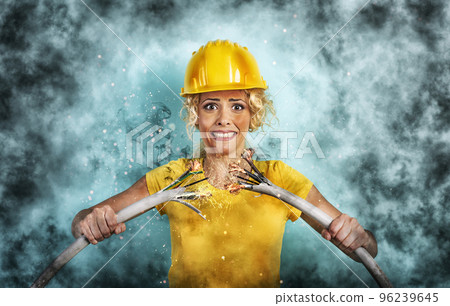 Worker girl with hat breaks an electric cable. Cyan background 96239645