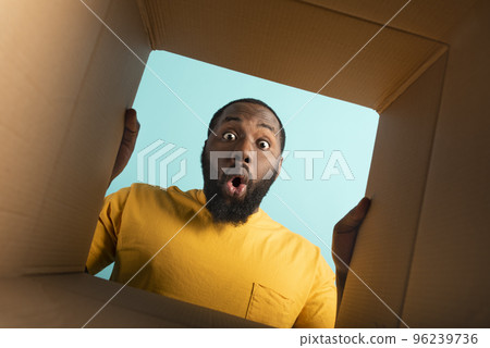 Happy boy receives a package from online shop order. happy and surprised expression. Blue background. Happy boy receives a package from online shop order. happy and surprised expression. Blue background. 96239736