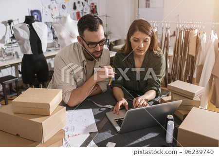 Seamstresses team ready to ship package to client with new clothes Seamstresses team ready to ship package to client with new clothes 96239740
