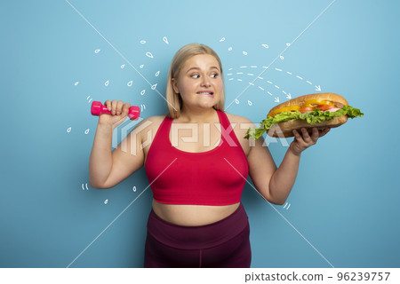 Fat woman does gym and want to eat a sandwich. Concept of food temptation 96239757