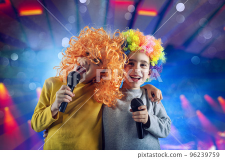 Two child sing a song with microphone and funny wig Two child sing a song with microphone and funny wig 96239759