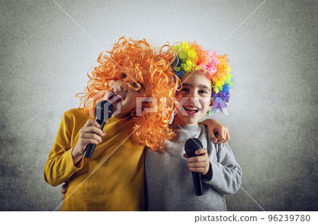 Two child sing a song with microphone and funny wig Two child sing a song with microphone and funny wig 96239780