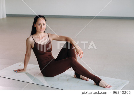 a woman in a brown suit does yoga in a fitness room . Healthy lifestyle, fitness, training, self-care 96240205