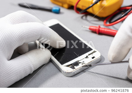 Technician hands working on broken smartphone for repair or replace new part on desk 96241876