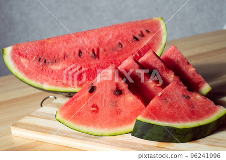 A sliced ripe watermelon is lying on a wooden table 96241996