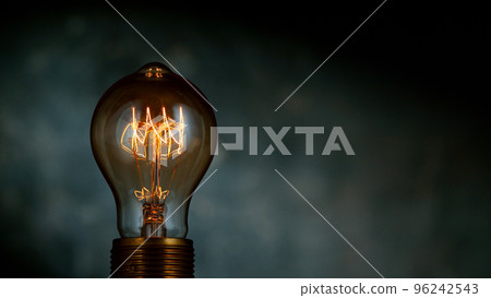 Close-up of shining light bulb, dark background Close-up of shining light bulb, dark background 96242543