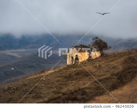 Old family crypt on a misty mountain slope. Old Erzi tower complex in the Jeyrah gorge, located on the extremity of the mountain range in Ingushetia, Russia. Old family crypt on a misty mountain slope. Old Erzi tower complex in the Jeyrah gorge, located on the extremity of the mountain range in Ingushetia, Russia. 96243020
