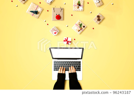 Person using a laptop computer with Christmas gift boxes Person using a laptop computer with Christmas gift boxes 96243187