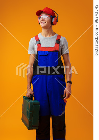 Portrait of young foreman worker with toolbox over yellow background 96243345