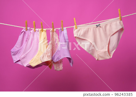 Female panties hanging on rope against pink studio background Female panties hanging on rope against pink studio background 96243385