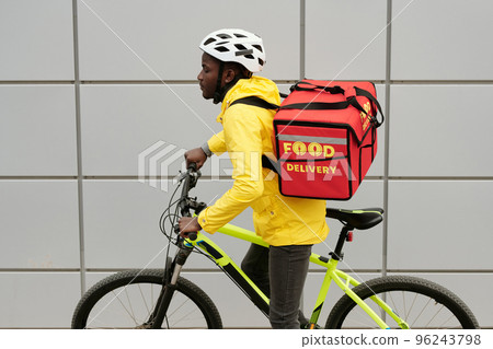 Side view of African American food delivery service worker in uniform 96243798