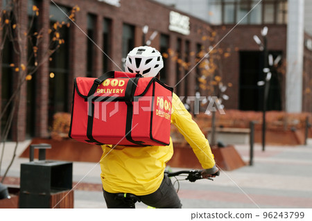 Back view of young deliveryman with red square backpack with food 96243799