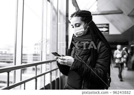 Girl in protective sterile mask on her face with a phone in quarantine city. Woman using the phone. Girl in protective sterile mask on her face with a phone in quarantine city. Woman using the phone. 96243882