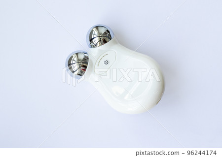 Microcurrent Facial Massager. Device for home use to fight aging and tighten the face on a pink background. The concept of microcurrents. Top view, flat plan 96244174