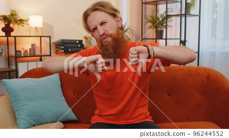 Upset young man showing thumbs down, dislike bad work, disapproval, dissatisfied feedback at home 96244552