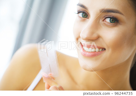 Teeth Whitening. Beautiful Smiling Woman Holding Whitening Strip. High Resolution Image Teeth Whitening. Beautiful Smiling Woman Holding Whitening Strip. High Resolution Image 96244735