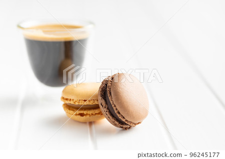 Sweet macaron dessert and coffee cup. Colorful macarons on white table. Sweet macaron dessert and coffee cup. Colorful macarons on white table. 96245177