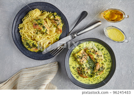 Chkemeruli on a dark plate with cutlery, sauce, olive oil and kitchen towel 96245483