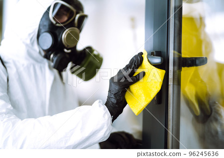 Man in protective hazmat suit washes door handles in office to preventing the spread of coronavirus. 96245636