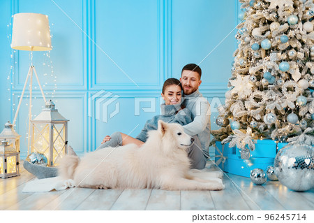 happy couple sitting and hugging near Christmas tree at home. hearth, home clothes and sweaters 96245714