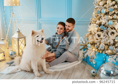 happy couple sitting and hugging near Christmas tree at home. hearth, home clothes and sweaters 96245715