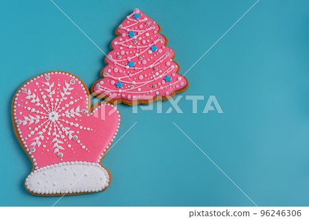New Year's goodies. Christmas mitten gingerbread pink and a Christmas tree on turquoise background. New Year's goodies. Christmas mitten gingerbread pink and a Christmas tree on turquoise background. 96246306