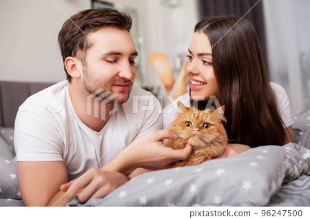 Happy sensual young couple lying in bed together Happy sensual young couple lying in bed together 96247500