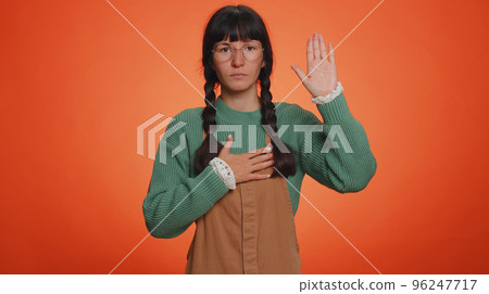 Sincere responsible young nerd woman raising hand to take oath, promising to be honest, tell truth Sincere responsible young nerd woman raising hand to take oath, promising to be honest, tell truth 96247717