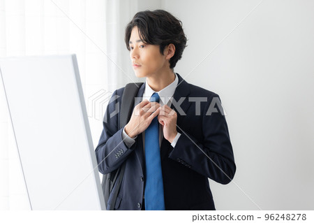 A young man in a suit getting dressed 96248278