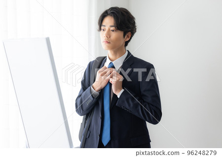 A young man in a suit getting dressed 96248279