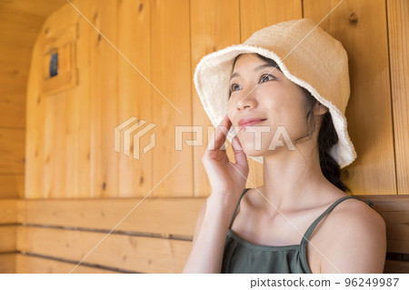 A young woman wearing a sauna hat and entering a sauna A young woman wearing a sauna hat and entering a sauna 96249987
