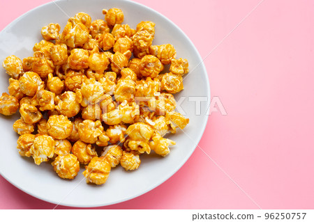 Honey caramel popcorn on pink background. Honey caramel popcorn on pink background. 96250757