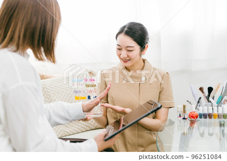 Japanese woman receiving counseling from a manicurist while looking at nail tips at a nail salon Japanese woman receiving counseling from a manicurist while looking at nail tips at a nail salon 96251084
