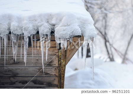 Close up view of icicles on the roof of an old wooden stable in winter Close up view of icicles on the roof of an old wooden stable in winter 96251101