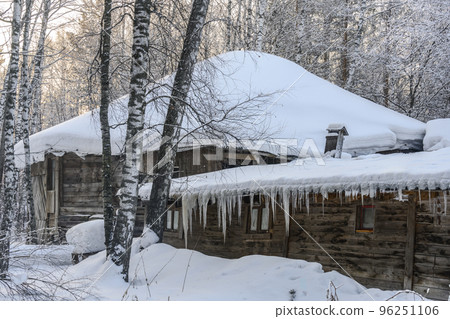 An old wooden house and stable with icicles on the roof in a birch snow-covered forest in winter An old wooden house and stable with icicles on the roof in a birch snow-covered forest in winter 96251106