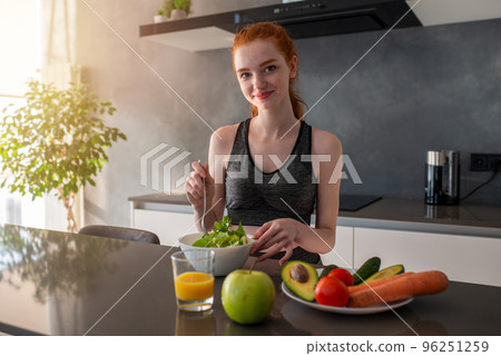 Athletic girl with gym clothes eats a salad in the kitchen 96251259