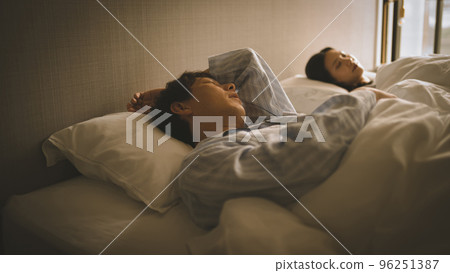 couple sleeping in twin beds 96251387