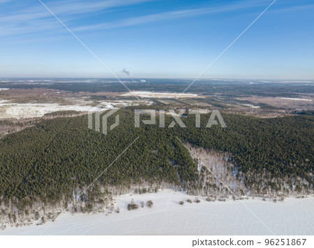 Snow-covered forest on lake shore with ice at sunset and the city on horizon, auerial view Snow-covered forest on lake shore with ice at sunset and the city on horizon, auerial view 96251867