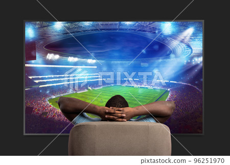 Viewer in front of a large TV relaxed on the armchair at home watching a sports game 96251970