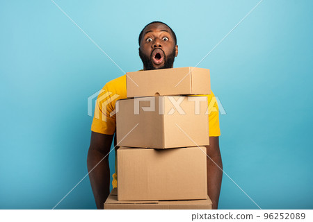 Man receives a lot of packages and has a surprised expression. Cyan background 96252089