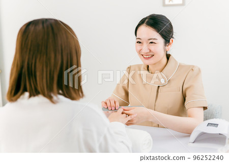 Manicurist sanding at nail salon and Japanese woman receiving treatment 96252240