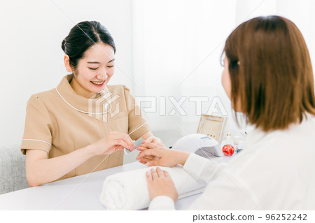 Manicurist sanding at nail salon and Japanese woman receiving treatment 96252242