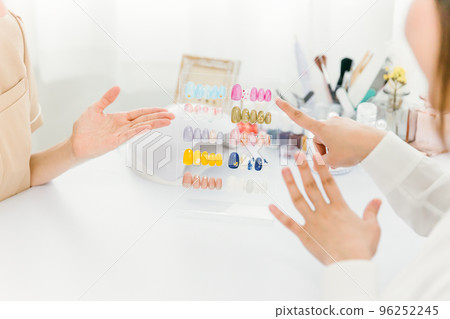 美甲師在美甲沙龍向一位女士解釋看指甲尖並選擇設計 96252245