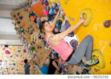 Woman climbing on rock-climbing wall 96252336